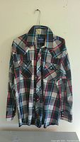 Front view of the long sleeve plaid Wrangler shirt with button closure and two chest pockets.