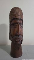 Front view of the carved wooden bust showcasing facial details and textured hair and beard.