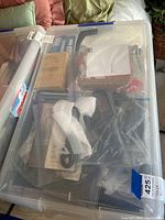 Plastic bin with various electronics and accessories packed inside sealed plastic bags.