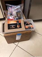 Wooden drawer with several packs of Duracell batteries and other small hardware items inside.