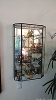 Full view of glass corner display case mounted on wall with multiple clown figurines visible inside.