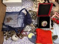 Drawer containing assorted costume jewelry in organza pouch, brooch, ring box