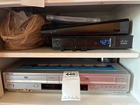 Sony DVD/VHS combo player SLV-0370P with RCA input cables and a Cisco digital device above on shelf