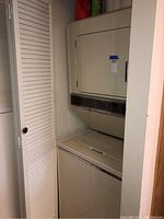 Full view of stacked Maytag washer and dryer in a recessed alcove area, showing the complete appliance and its size relative to surrounding walls.