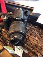 Front view of Nikon D5000 with lens and Nikon lens cap on grassy surface