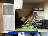 Shelf with various items, USB cables including green flat style cable, black power bank, and small USB drives visible in plastic packaging