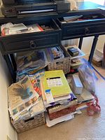 Photo showing an overview of the desk with drawers filled with scrapbook papers, embellishments, and crafting supplies with baskets underneath holding additional materials.