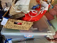 Photo of plastic container filled with a variety of scrapbooking supplies such as stickers, letters, and acrylic album blanks.