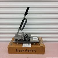 Manual Befen slicer machine on original box with instruction leaflet, showing slicer handle, blade, and base.