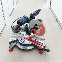 Front angled view of Bosch miter saw showing red 12-inch blade, aluminum table, scale markings and sliding rails