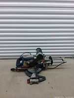 Front angle view of Bosch sliding compound miter saw showing base, rails, handle, and clamp