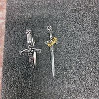 Image showing both the sword pendant ring and sword motif bracelet on a black textured surface.