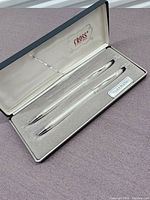 Silver plated Cross pen and pencil set in original case, showing pen and pencil resting inside padded interior with logo inside lid.