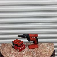 Full view of screwdriver body, battery pack and charger on mottled surface against metal background