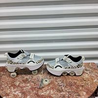 Pair of kids rollerblade shoes size 33 with built in wheels and adjustable straps, placed on marble surface with extra wheels in front.