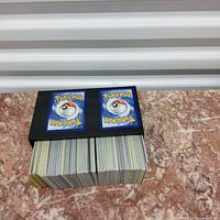 Stack of over 500 Pokémon trading cards seen from the back showing classic Poké Ball design.