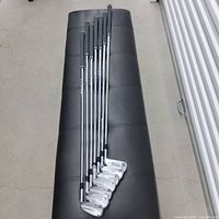 Seven TaylorMade P770 irons laid out on bench showing full set