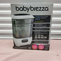 Front of the retail box showing product name, image of the sterilizer holding bottles, features summary.
