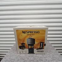 Front view of the original retail box of Nespresso Vertuo Next coffee machine with branding and product image.