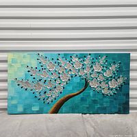 Front view of large rectangular oil painting depicting a curved tree with white blossoms on a blue-green textured background.