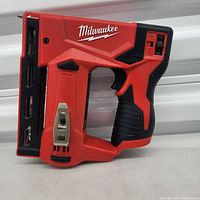 Side profile of Milwaukee M12 3/8 Crown Stapler showing design, battery slot, and handle grip.