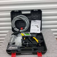Open kit showing black and yellow AiHand power washer, 21V battery, coiled grey hose, bubble-wrapped accessories, and instruction manual inside molded plastic carrying case.