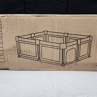 Box side showing a line drawing of the large square toddler playpen with mesh sides, padded corner posts, and a small door opening.