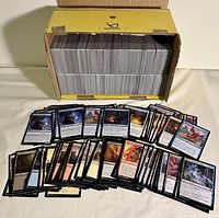 Box filled with Magic: The Gathering cards, with some cards fanned out in front showing artwork and text.