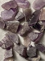 Close-up view of multiple rough amethyst stones showing purple coloration and rough natural surfaces
