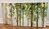 Photo of one canvas showing birch tree trunks with green and yellow leaves in an abstract forest style, on wood floor.