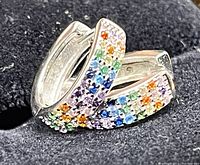 Close-up photo of one round hoop earring showing colorful zircon stones on silver base and hinge clasp