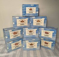 Ten boxed jar candle toppers stacked and arranged, showing all in original packaging with visible labels naming decorative themes.