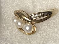 Top angle showing five white pearls in graduated sizes flanked by a small diamond row on gold band