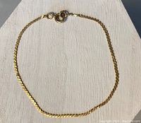 Full view of the gold bracelet laid out flat, showing its length and chain design.