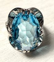 Front view of oval blue faceted gemstone in 14K HGE ring showing stone clarity, cut and prong setting