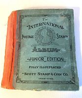 Front cover of the 1933 Scott Stamp & Coin Co International Postage Stamp Album Junior Edition showing wear, discoloration, and a loose or missing spine binding and back cover.
