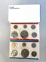 Two sealed 1977 US Mint Coin Sets in original plastic packaging with red and blue borders. Sets include six coins each and come with original envelope and inserts.