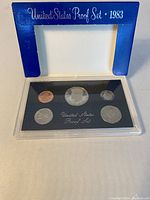 1983 United States proof coin set in original blue display frame showing front view of plastic-encased coins on black background.