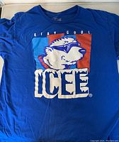 Photo of blue ICEE Stay Cool T-shirt showing front graphic featuring the ICEE polar bear wearing sunglasses with red and light blue background and large ICEE text.