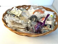 Wide view of costume jewelry in a wicker basket showing various earrings and bracelets in clear plastic bags and some loose pieces.