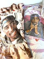 Two medium size tie-dye style T-shirts featuring photo prints of Tupac Shakur from Poetic Justice movie laid out side-by-side