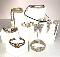 Full collection showing multiple bracelets, two pairs of earrings, and butterfly pendant necklace displayed on white stands.