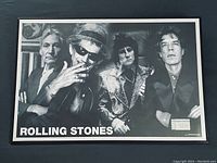 Framed black and white vintage Rolling Stones poster from 2002 showing all four band members, with visible wear and a ticket stub affixed in lower right.
