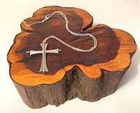 Sterling silver cross pendant necklace displayed on a wood base, showing full necklace length and cross pendant size.