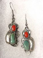 Front view of the pair of sterling silver earrings showing intricate design with red and green colored stones and feather motif.