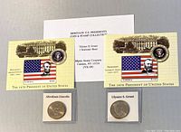 Full lot showing both coins in protective cases and both $100 souvenir sheets with white card insert text.