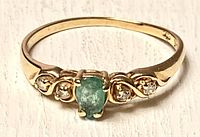 Front view showing emerald center and diamond side stones in swirl setting.