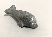 Front angled view showing the carved seal sculpture in gray soapstone with visible wear and fine engraved facial details.