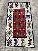 Full view of the Kilim rug laid flat on a gray floor showing overall design and condition.