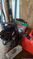 Photo showing the Craftsman pressure washer with visible handle, wheels, and nearby items including a gas can and user manual.